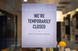 A printed sign is taped to a storefront business in downtown Chicago indicating the business is temporarily closed due to Covid-19 coronavirus pandemic.