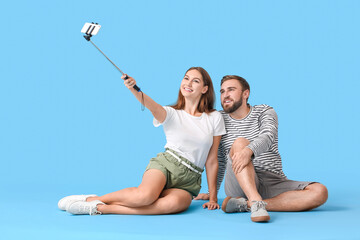 Wall Mural - Young couple taking selfie on color background