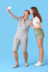 Wall Mural - Young couple taking selfie on color background