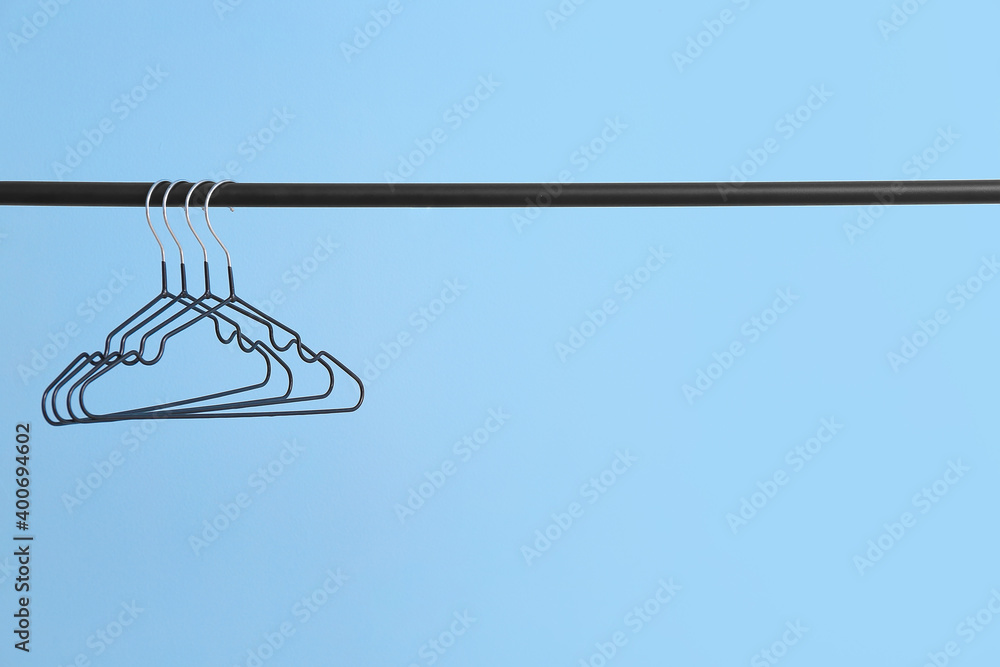 Rack with clothes hangers on color background