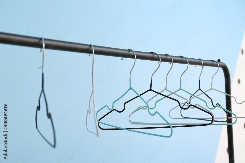 Rack with clothes hangers on color background