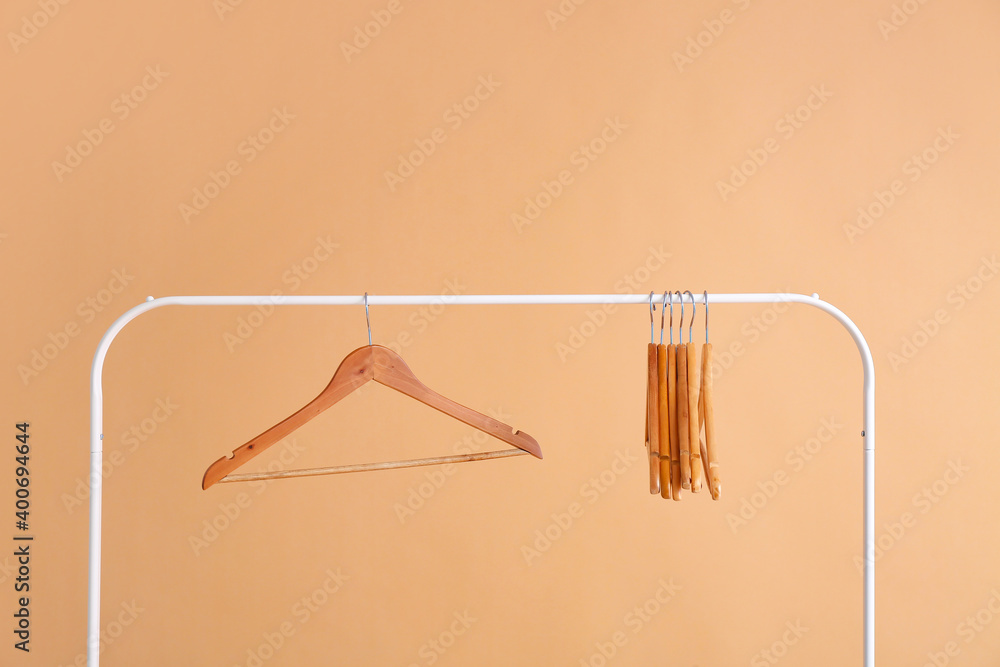 Rack with clothes hangers on color background