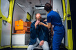 © Anna Kosolapova - A paramedic gives an oxygen mask to an injured man sitting in an ambulance car.