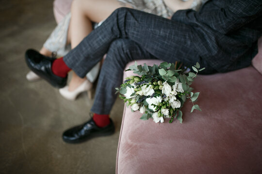 Wedding bouquet and feet of groom and bride