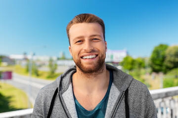 Wall Mural - fitness, sport and people concept - portrait of happy smiling young man outdoors