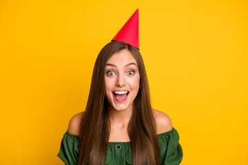 Poster - Close-up portrait of lovely amazed cheerful brown-haired girl festal occasion wearing paper cap isolated over bright yellow color background