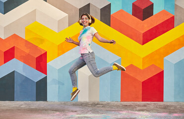 Wall Mural - Excited young woman jumping against geometric wall