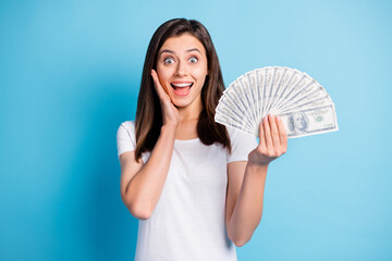 Sticker - Photo of young shocked happy smiling amazed lovely girl with money hold hand cheek isolated on blue color background