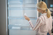 © zinkevych - Woman in striped shirt choosing fridge in a showroom