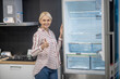 © zinkevych - Woman in striped shirt demonstrating a new fridge in a showroom
