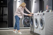 © zinkevych - Woman in striped shirt choosing a washing machine in a showroom