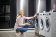© zinkevych - Female customer in striped shirt choosing a washing machine in megastore
