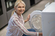 © zinkevych - Woman in striped shirt examining a washing machine in a showroom