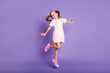 Full body photo of dreamy positive little girl jump up air wear pink shoes isolated on purple color background