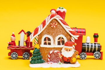 Sticker - toy christmas house with santa claus train on a yellow background