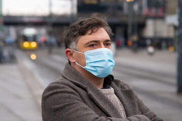 Wearing protective masks outdoors in the city. Disease outbreak, coronavirus covid-19 pandemic. Headshot of a man covering his face with a medical mask to protect his nose and mouth