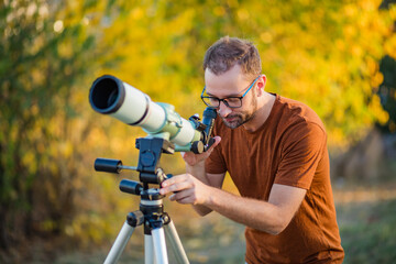 Wall Mural - amateur astronomer looking at the sky with a telescope.