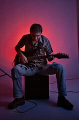 The guitarist play music with combo amplifier in beautiful red hall.  