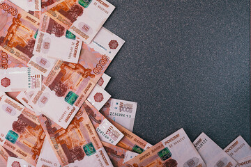 Russian cash banknotes of five thousand rubles, scattered on a gray background