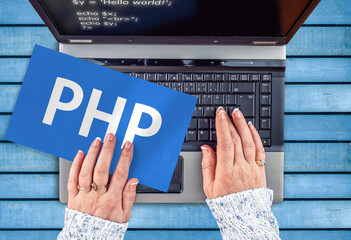php programing language. woman hands on laptop and php word on paper sheet