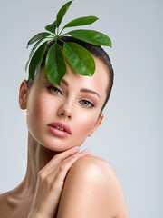 Wall Mural - beautiful woman with green leave near face and body. closeup girl's face with green leave. skin care