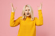 © ViDi Studio - Angry irritated elderly gray-haired blonde woman lady 40s 50s years old in yellow casual sweater standing spreading hands swearing screaming isolated on pastel pink color background studio portrait.