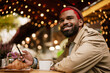 © Drobot Dean - Young african american happy man using cellphone in cafe outdoors