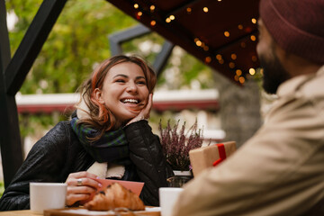 Multinational couple smiling while drinking coffee in cafe outdoors