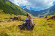 © pijav4uk - Sensual pretty girl in long blue white dress sits on a rock and dreaming against the high mountains backgdrop. Woman sitting near Transfegerasan, one of the most spectacular mountain road in the world