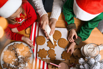 Canvas Print - Mother and her little children decorating tasty Christmas cookies at wooden table, top view