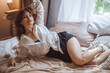 © Smeilov - sexy girl lying on the bed in a white shirt and skirt