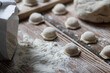 © Margo - Cooking dumplings. Raw dumplings lie on a wooden board. Nearby lies flour, rolling pin and dough against a background of wood.