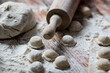 © Margo - Cooking dumplings. Raw dumplings lie on a wooden board. Nearby lies flour, rolling pin and dough against a background of wood.