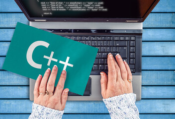 Wall Mural - c++ programing language . woman hands on laptop and word c++ on paper sheet