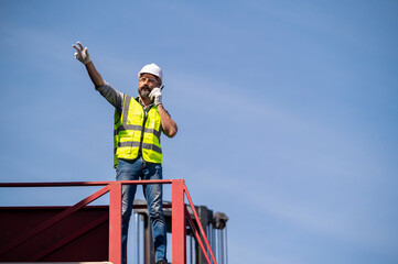 Wall Mural - Logistics engineer stand on and Pointing up around Shipping container stacker in commercial transport port