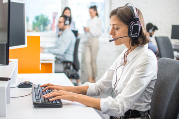 Wall Mural - Attractive helpline worker woman using computer in call center office.