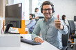 © Bojan - Cheerful handsome call center worker showing thumbs up in a call center.