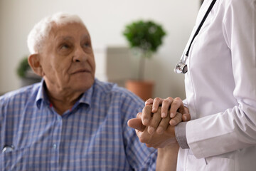 Wall Mural - Crop close up of female nurse touch hold senior male patient hand show empathy and care during treatment. Supportive woman doctor comfort cheer mature man in hospital. Elderly healthcare concept.