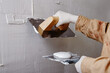 Close up of construction worker plastering and smoothing wall with trowel and putty knife.