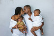 © Ursula Page - A beautiful African-American young family with two children. The oldest son is a toddler and the new infant newborn son is only a few weeks old. Mom and Dad are kissing