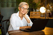 beautiful stylish woman aged in glasses at the table with a laptop