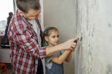 Father With Kid Repairing Room Together And Unhanging Wallpaper Together