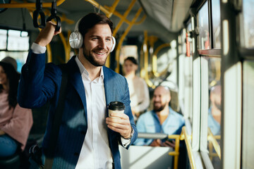 Wall Mural - Happy businessman listening music over headphones while commuting by bus.