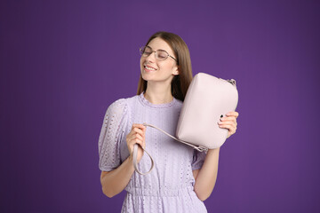 Wall Mural - Young woman with stylish pink bag on purple background