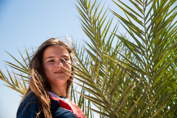 Wall Mural - woman wearing sunglasses posing with palm tree. Portrait of beautiful teenage girl