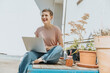 © Mareen Fischinger/Westend61 - Woman laughing while using laptop sitting on terrace during sunny day
