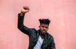 © Marco Govel/Westend61 - Serious man with arm raised listening music while standing against pink wall