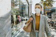 © Mareen Fischinger/Westend61 - Woman wearing protective face mask walking on street during sunny day