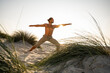 © UWE_UMSTAETTER/Westend61 - Shirtless young man practicing warrior 2 position yoga at beach against clear sky during sunset