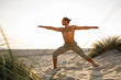 © UWE_UMSTAETTER/Westend61 - Shirtless man practicing warrior 2 position yoga at beach against clear sky during sunset